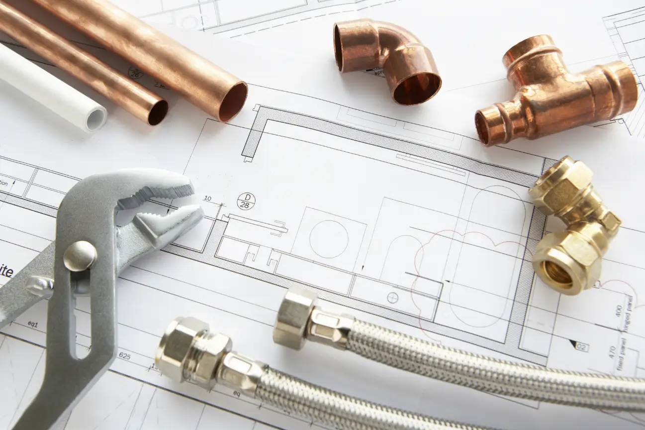Plumbing tools and fittings on building plans showing what our plumbing company East Auckland can do for you
