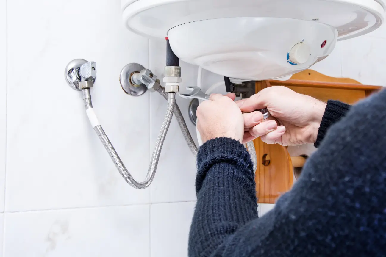 Plumber adjusting water heater pipes during a plumbing service for Taylor Plumbing East Auckland
